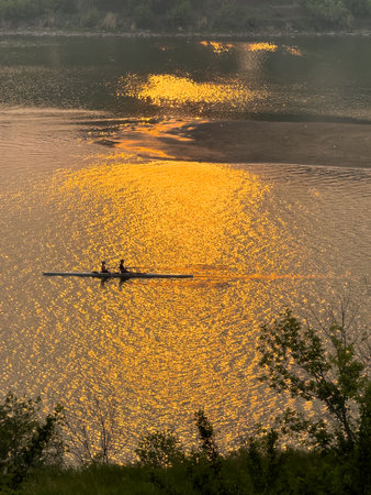 Boat is floating on a lake at sunset. The water is calm and the sky is orangeの写真素材