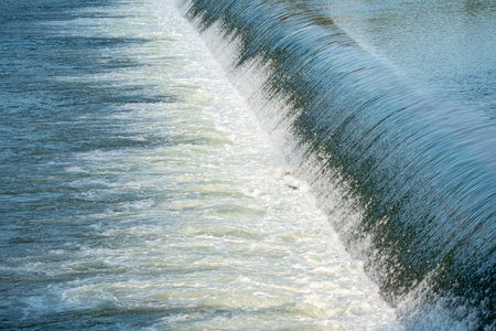 Waterfall is shown in the image, with the water flowing down a steep slope. The water is white and clear, and it is a powerful force of nature. Concept of awe and wonder at the beautyの写真素材