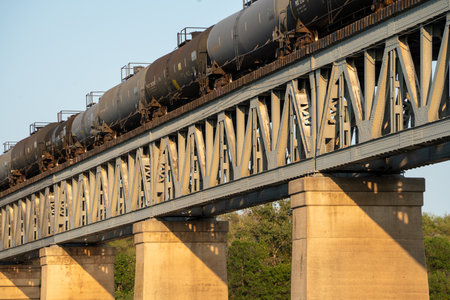 Train is crossing a bridge with a lot of metal. The bridge is very long and has a lot of metal