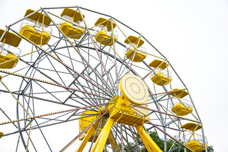 Yellow and white Ferris wheel with many seats. The wheel is in the center of the image