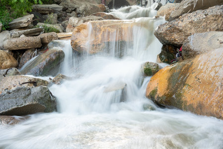 Stream of water flows over a rocky surface. The water is clear and calm, and the rocks are large and...