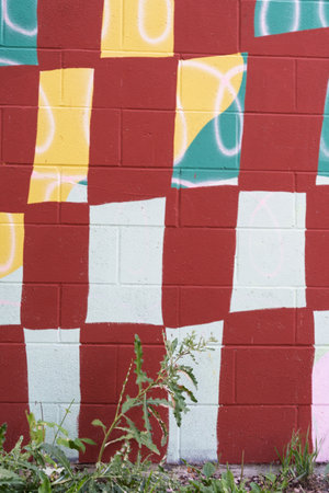 Wall with a checkered pattern and graffiti on it. The wall is red and whiteの写真素材
