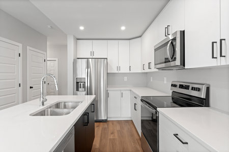 Kitchen with a white counter and stainless steel appliances. The kitchen is clean and well-organized