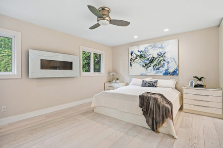 Large white bed with a blue and white painting on the wall. The room is decorated in a minimalist...