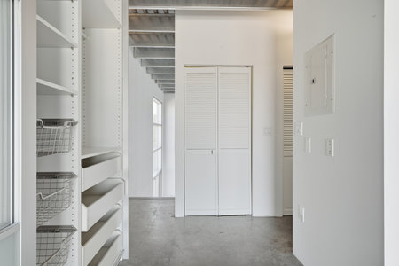 White hallway with a white closet and white cabinets. The hallway is empty and the closet is unopenedの写真素材