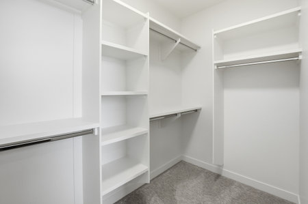 White closet with shelves and a hanging rod. The closet is empty and clean. The white color of the closet gives a sense of calmness and simplicityの写真素材