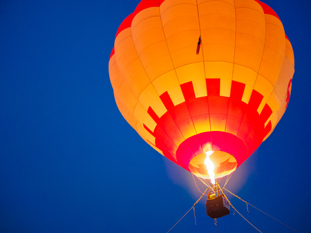 colorful of Hot air balloon with fire and dark blue sky background in eveningの写真素材