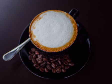 closeup cappuccino coffee on black cup with coffee bean on dark backgroundの写真素材