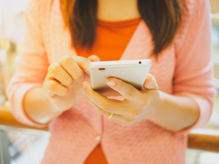 Pretty Young woman using smart phone. Female working on cell phone in big shopping mallの写真素材