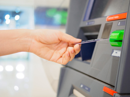 Close-up of woman's hand inserting debit card into an ATM machine. Horizontal shot.の写真素材
