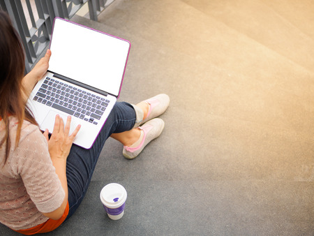 Pretty Young woman using laptop computer. Female working on laptop in an outdoor cafe.の写真素材