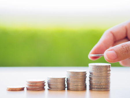 abstract money saving hand put a coin on stacking coinsの写真素材