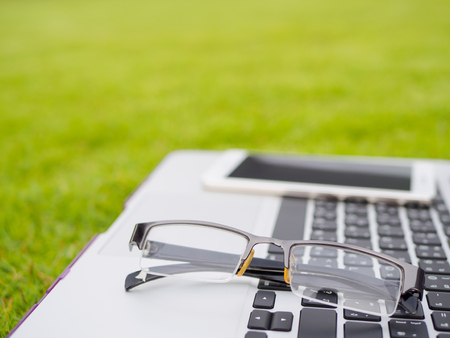 Laptop, notebook,gresses and smartphone on the green grassの写真素材