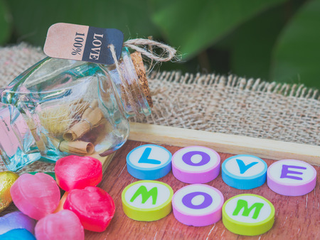 love mom spelled with colorful alphabet blocks and a red heart isolated on wooden board and  sack - Mothers Dayの写真素材