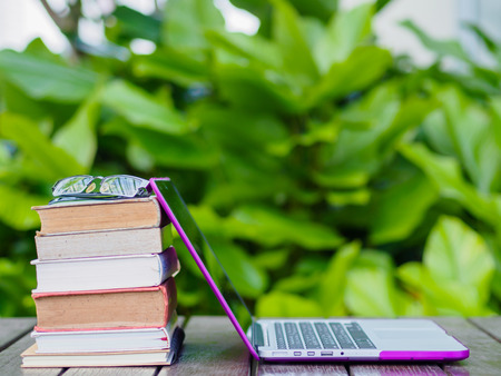 Stack of books with laptop on wood table outdoorの写真素材