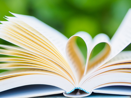 book on table in garden with top one opened and pages forming heart shapeの写真素材
