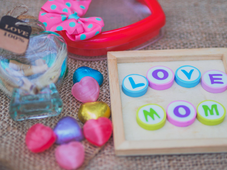 love mom spelled with colorful alphabet blocks and a red heart isolated on wooden board and  sack - Mothers Dayの写真素材