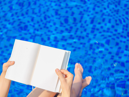 woman reading and relaxing near luxury swimming poolの写真素材