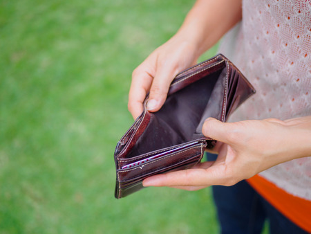 Unhappy bankrupt woman with empty wallet. Young woman shows her empty wallet. Bankruptcyの写真素材