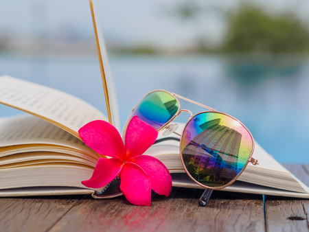 Book and sunglasses, blue water background, summer and tropical travel destinations conceptの写真素材