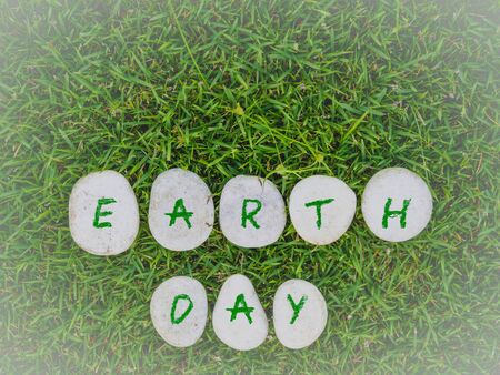 earth day concept. stone with green text on green gress backgroundの写真素材