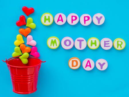mother's day concept.  HAPPY MOTHER DAY alphabet with colorful heart and red bucket on blue backgroundの写真素材