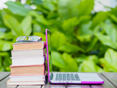 Stack of books with laptop on wood table outdoorの写真素材