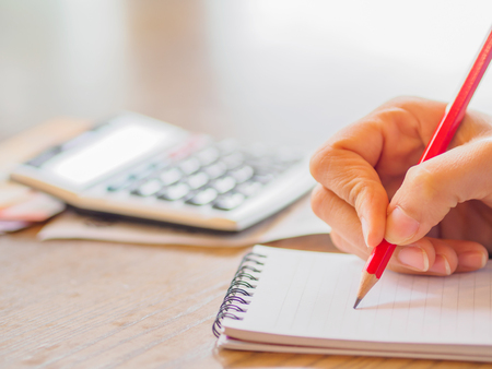 Woman using calculator and thinking about cost on desk at home office.の写真素材