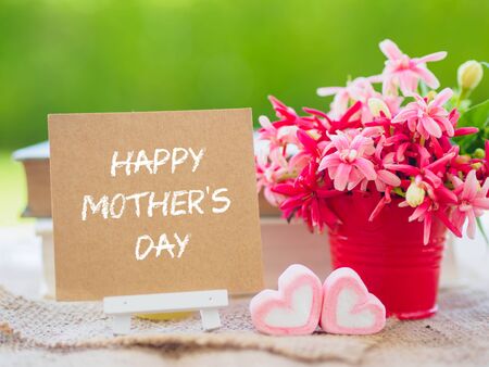 mother's day concept. Poster mock up template with flower bouquet, marshmallow in the shape of heart and books over green background with Happy mother's day textの写真素材