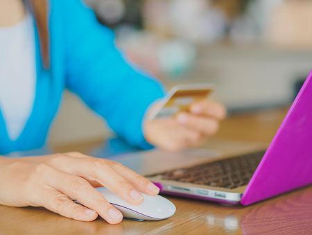 Pretty Young womans hands holding a credit card and using tablet, smartphone and laptop computer for online shopping. Online payment. Female working on smart phone laptop in a cafe.の写真素材