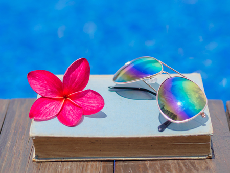 Book and sunglasses, blue water background, summer and tropical travel destinations conceptの写真素材
