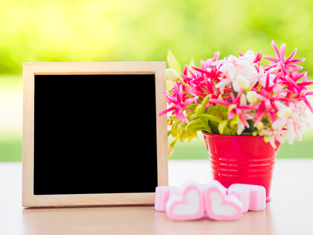 Poster mock up template with flower bouquet, marshmallow in the shape of heart and books over green backgroundの写真素材