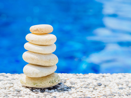 Balance Stones stacked to pyramid in the soft blue water background to Spa ideas design or freedom and stability concept on rocks.の写真素材