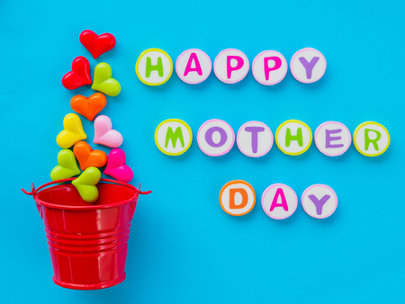 mother's day concept.  HAPPY MOTHER DAY alphabet with colorful heart and red bucket on blue backgroundの写真素材