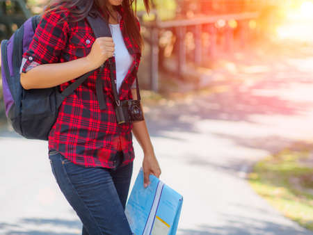 Happy Asian girl holding map with backpack in the road and forest background, Relax time on holiday concept travel ,color of vintage tone and soft focusの写真素材
