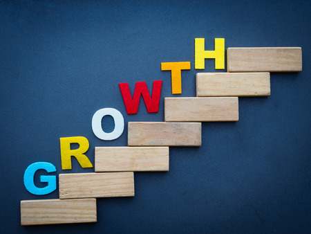 Wood block stacking as step stair with colorful of "GROWTH" word on it in black background. Business concept for success process.の写真素材
