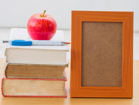 World Book Day concept. Red apple and pen put on stack of old books with photo frameの写真素材