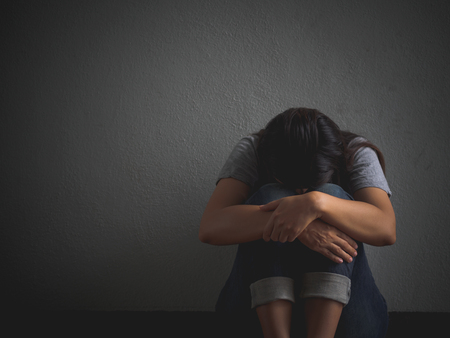 sad woman hug her knee and cry. Sad woman sitting alone in a empty room.の写真素材