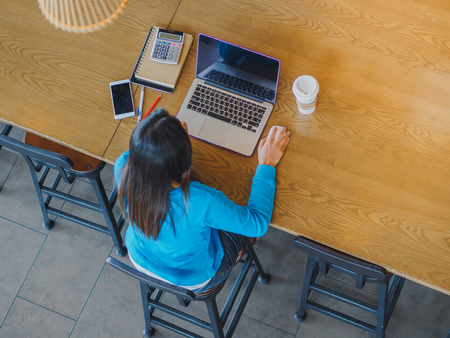 Pretty Young woman using laptop computer. Female working on laptop in an indoor cafe.の写真素材