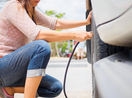 driver checking air pressure and filling air in the tires close upの写真素材