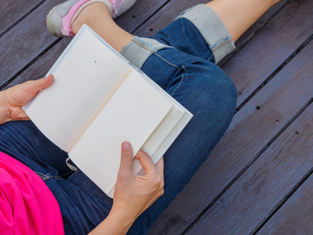 Woman with book sitting on wooden floorの写真素材