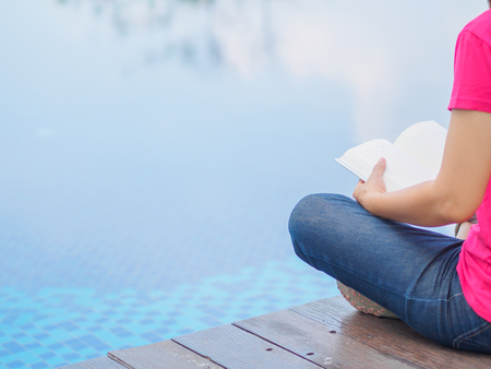 woman reading and relaxing near luxury swimming poolの写真素材