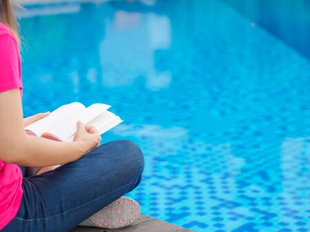 woman reading and relaxing near luxury swimming poolの写真素材