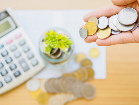 abstract money saving small baby tree with glass jar Coins with calculator on table with green tree backgroundの写真素材