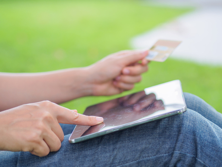 Close-up woman's hands holding a credit card and using tablet pc for online shoppingの写真素材