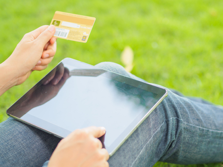 Close-up woman's hands holding a credit card and using tablet pc for online shoppingの写真素材