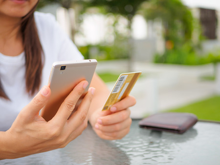 Online payment, women's hands holding a credit card and using smart phone for online shoppingの写真素材