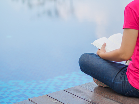 woman reading and relaxing near luxury swimming poolの写真素材