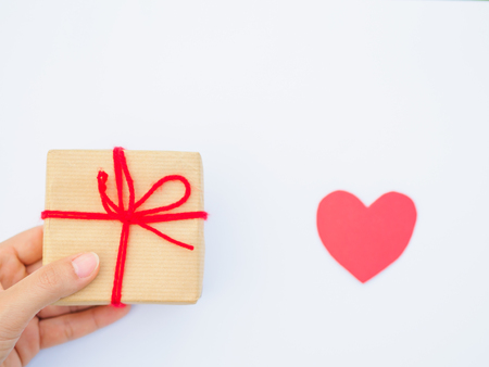 Hands holding beautiful gift box with red heart, female giving gift, Christmas holidays and greeting season concept, shallow dofの写真素材