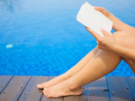 woman reading and relaxing near luxury swimming poolの写真素材